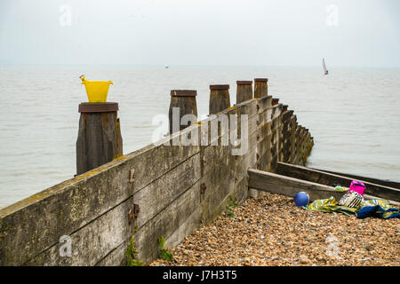 Godet jaune, boule, et les serviettes sont disponibles sur la plage de Stoney à Whitstable Banque D'Images