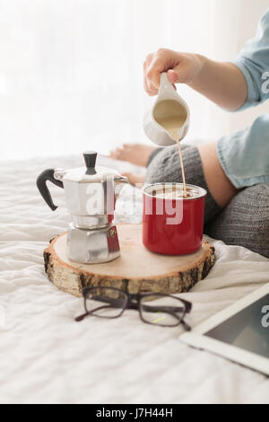 Close-up of young woman pouring lait en grande tasse de café rouge Banque D'Images