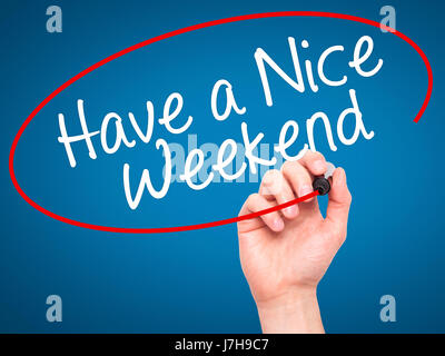 La main de l'homme ont écrit un bon week-end avec marqueur noir sur l'écran visuel. Isolé sur le bleu. Le commerce, la technologie, internet concept. Image Banque D'Images