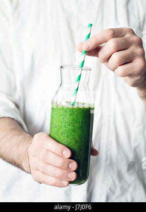 Smoothie vert. Man hands holding bouteille avec des smoothie vert detox. Vue rapprochée, selective focus Banque D'Images