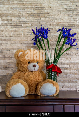 L'ours en peluche et une boucket d'iris en vase en verre. Cadeau Fête des Mères Banque D'Images