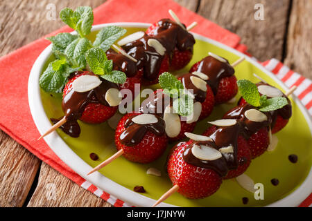 Fraises d'été dessert avec du chocolat, menthe et amandes sur une plaque horizontale. Banque D'Images