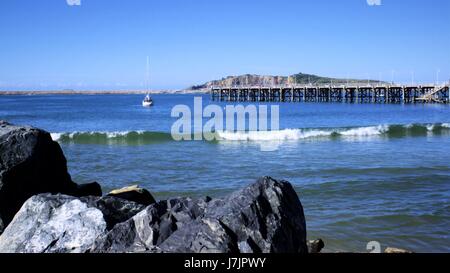 Jetée ou Pier au-dessus de la mer de rochers, vagues, yacht, bateau, hill loin dans la distance. Vue de la jetée de Coffs Harbour en Australie Banque D'Images