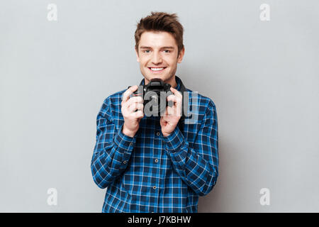 Beau Jeune homme tenant son appareil photo en mains isolées Banque D'Images