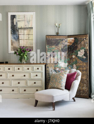 Chaise longue dans la chambre avec du papier peint Farrow & Ball Lattice. L'écran est chinois et le style art déco applique murale ont été ourced par retrouvius Banque D'Images