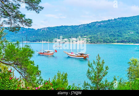 La vue sur le port de plaisance en Dakapo à travers les branches vertes et fleurs de Yoruk park, Kemer, Turquie. Banque D'Images