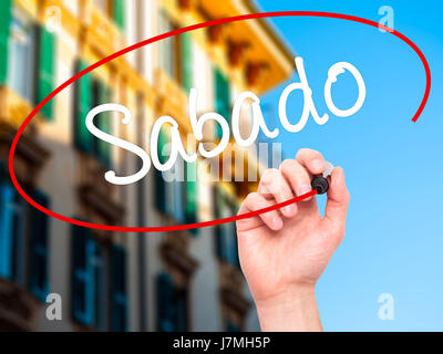 Man main écrit Sabado (samedi en espagnol/portugais) avec marqueur noir sur l'écran visuel. Isolé sur la ville. Le commerce, la technologie, internet concept. Banque D'Images