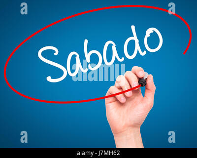 Man main écrit Sabado (samedi en espagnol/portugais) avec marqueur noir sur l'écran visuel. Isolé sur le bleu. Le commerce, la technologie, internet concept. Banque D'Images