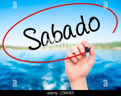Man main écrit Sabado (samedi en espagnol/portugais) avec marqueur noir sur l'écran visuel. Isolé sur la nature. Le commerce, la technologie, internet concep Banque D'Images