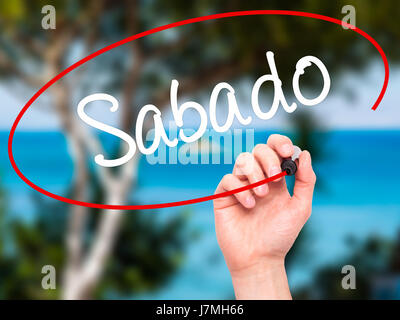 Man main écrit Sabado (samedi en espagnol/portugais) avec marqueur noir sur l'écran visuel. Isolé sur la nature. Le commerce, la technologie, internet concep Banque D'Images
