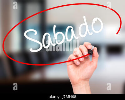 Man main écrit Sabado (samedi en espagnol/portugais) avec marqueur noir sur l'écran visuel. Isolé sur bureau. Le commerce, la technologie, internet concep Banque D'Images