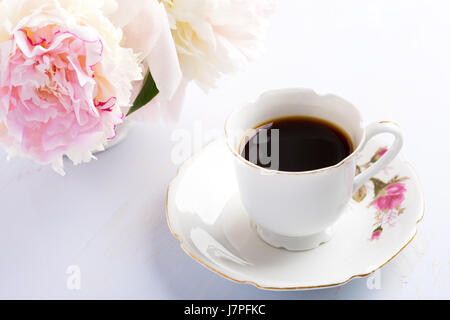 Nature morte à la tasse de café et de fleurs (pivoines) sur table en bois lilas clair. Banque D'Images