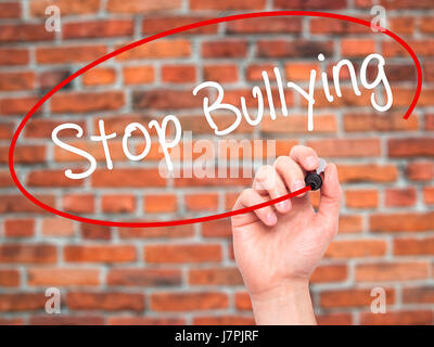 Man main écrit mettre fin à l'intimidation avec marqueur noir sur l'écran visuel. Isolé sur des briques. Le commerce, la technologie, internet concept. Stock Photo Banque D'Images