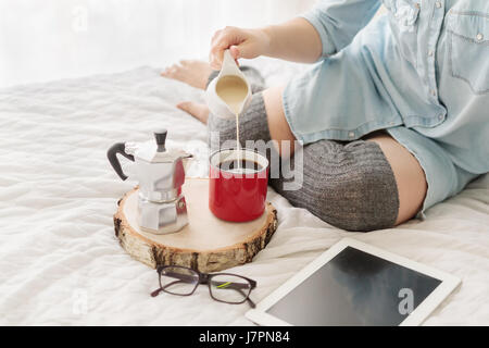 Close-up of young woman pouring lait en grande tasse de café rouge Banque D'Images