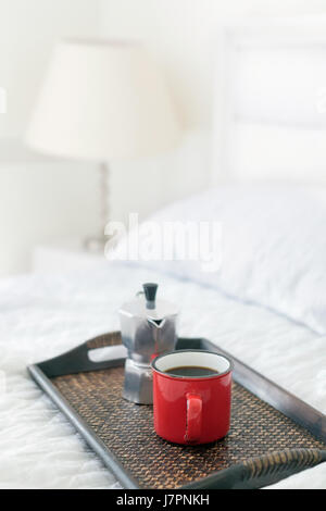 Tasse de café rouge avec percolateur en acier on bed Banque D'Images