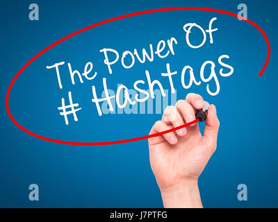 Man main écrit le pouvoir des Hashtags avec marqueur noir sur l'écran visuel. Isolé sur le bleu. Le commerce, la technologie, internet concept. Stock Photo Banque D'Images