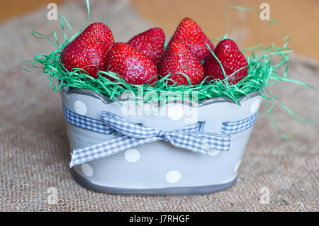 Frais et délicieux des fraises dans un beau vase en céramique avec ruban sur la texture d'un sac Banque D'Images