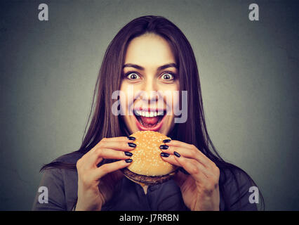 La restauration rapide est mon préféré. Woman eating a hamburger appréciant le goût Banque D'Images