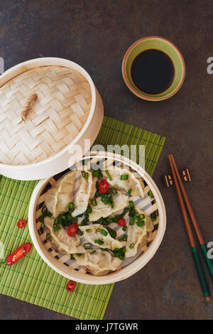 Gyoza potstickers ou boulettes en bateau à vapeur de bambou avec des tranches d'oignon de printemps et sauce Ponzu. Vue de dessus, l'espace vide Banque D'Images