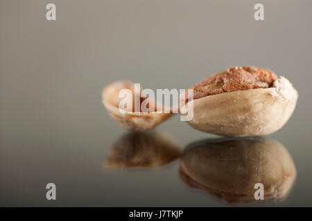 Pistache ouverte sur une plaque de verre avec shell adjacent. Banque D'Images