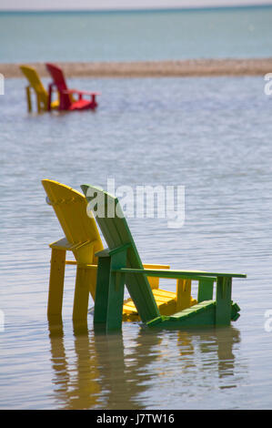 Chaises Muskoka partiellement immergé dans l'eau et le sable après les inondations printanières et des eaux du lac à Toronto, Ontario, Canada Banque D'Images