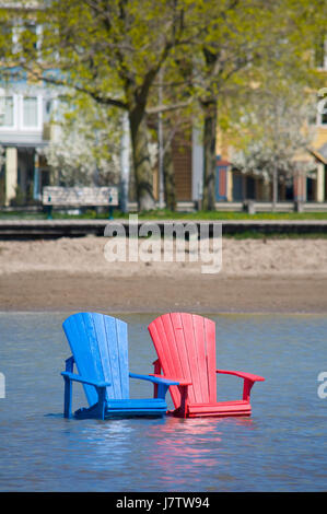 Chaises Muskoka partiellement immergé dans l'eau et le sable après les inondations printanières et des eaux du lac à Toronto, Ontario, Canada Banque D'Images