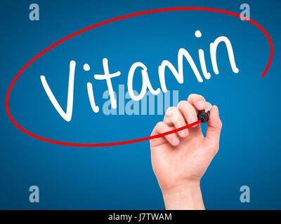 Man main écrit vitamine avec marqueur noir sur l'écran visuel. Isolé sur le bleu. Le commerce, la technologie, internet concept. Stock Photo Banque D'Images