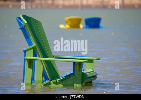 Chaises Muskoka partiellement immergé dans l'eau et le sable après les inondations printanières et des eaux du lac à Toronto, Ontario, Canada Banque D'Images