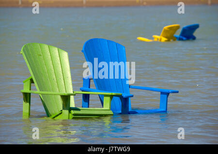 Chaises Muskoka partiellement immergé dans l'eau et le sable après les inondations printanières et des eaux du lac à Toronto, Ontario, Canada Banque D'Images