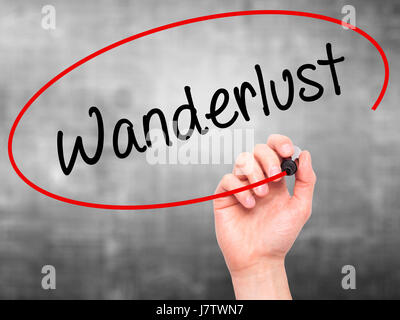 Man main écrit Wanderlust avec marqueur noir sur l'écran visuel. Isolé sur le gris. Le commerce, la technologie, internet concept. Stock Photo Banque D'Images