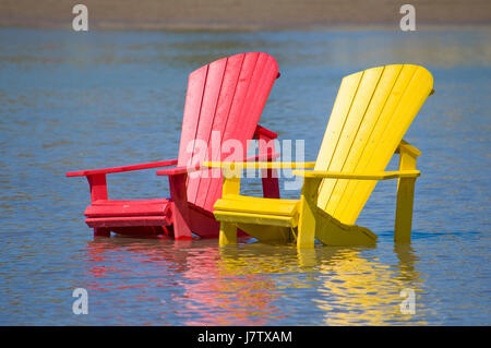 Chaises Muskoka partiellement immergé dans l'eau et le sable après les inondations printanières et des eaux du lac à Toronto, Ontario, Canada Banque D'Images