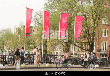 Les gens circuler à bicyclette suivant l'Ajax flagas sur la rue à Prinsengracht à Amsterdam, Pays-Bas le 23 mai 2017. Les partisans d'Ajax attendre sur t Banque D'Images