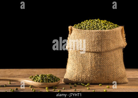 Close up de haricots mungo dans petit sac en bois sur table en bois. Isolé sur fond noir Banque D'Images