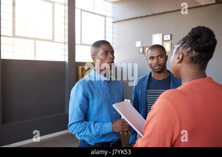 L'Afrique de l'accent des collègues de travail parler ensemble dans un bureau d'affaires Banque D'Images