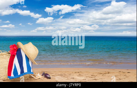 Serviette de plage et un chapeau de paille sur la plage de sable de l'été sac bannière, relaxation et vacations concept Banque D'Images