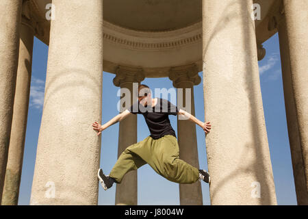 Jeune homme monte le miel des colonnes. Parkour dans l'espace urbain. Sport dans la ville. Activités sportives en plein air. L'acrobatie Banque D'Images