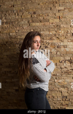 Sad girl bras croisés appuyé contre le mur Banque D'Images