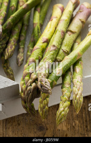 Jeu de matières, non cuit asperges vertes, légumes en boîte blanche sur fond de table rustique Banque D'Images