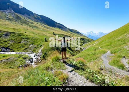 Femme debout sur le sentier dans la montagne dans les Alpes et d'élever ses bras, parc naturel de l'Oisans, France, Europe Banque D'Images