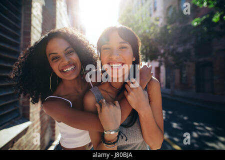 Portrait de deux jeunes femmes sur la rue de la ville d'avoir du plaisir. Amis de sexe féminin sur route embrassant et smiling outdoors. Banque D'Images