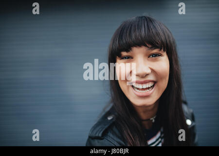 Close up portrait of young woman laughing contre fond gris. Belle hispanique modèle féminin s'amusant à l'extérieur. Banque D'Images