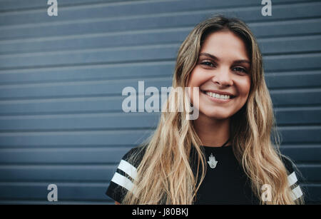 Close up portrait of smiling woman standing contre mur gris. Beau portrait jeune femme à la caméra et au sourire.