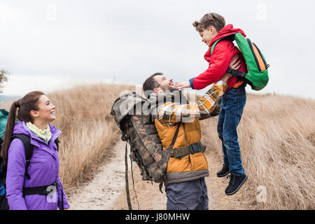 Side view of young smiling woman looking at heureux père tenant son petit fils Banque D'Images