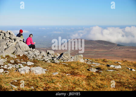 L'Irlande, le comté de Fermanagh, Cuilcagh Mountain Park, les randonneurs assis au bord d'un cairn préhistorique profitant de la vue depuis le sommet de Cuilcagh Pe Banque D'Images