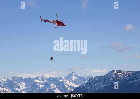 Zermatt, Suisse - 13 Avril 2017 : Un hélicoptère transportant du béton pour un chantier de construction dans les montagnes suisses Banque D'Images