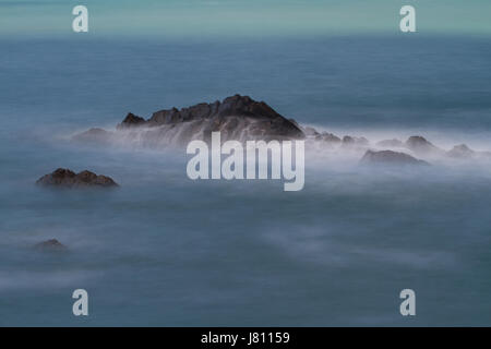 Vagues se briser sur les rochers s'avançant dans la mer -longue exposition-Devon, UK Banque D'Images