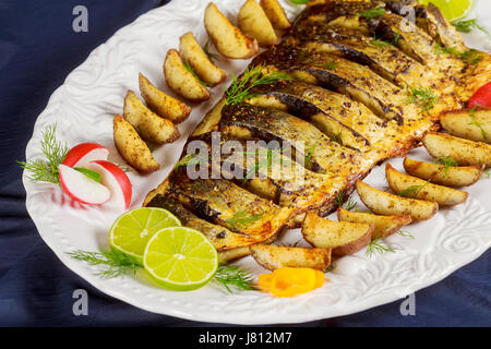 Le poisson grillé avec pommes de terre rôties et légumes sur la plaque Banque D'Images