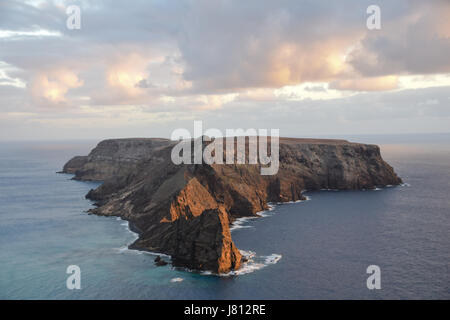 Coucher du soleil réfléchissant sur'Ilheu da Cal île inhabitée au sud de Ponta da Calheta, Porto Santo Madère avec à droite sur l'horizon Banque D'Images