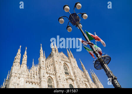 L'Italie, Lombardie, Milan. La cathédrale de Milan ou Duomo, une section de la façade avec un lampadaire orné de drapeaux italiens. Banque D'Images