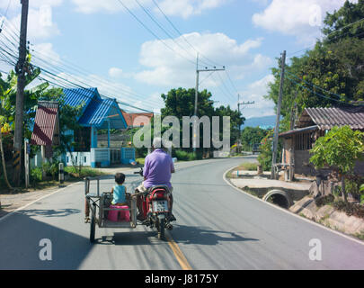 Un jeune garçon équitation dans un scooter's side-car près de Chiang Rai. Banque D'Images